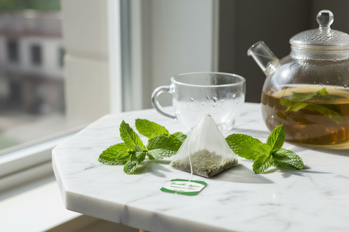 Breathe Again Moroccan Mint tea bag with fresh mint leaves and glass teapot in bright natural light